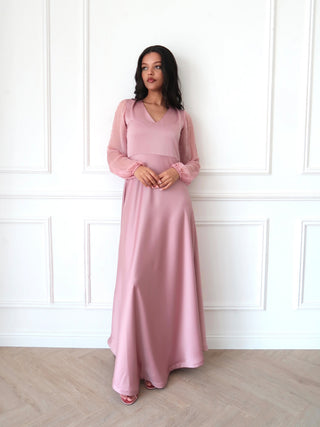 Blush pink chiffon and satin dress with flowing silhouette and sheer long sleeves in soft elegant interior