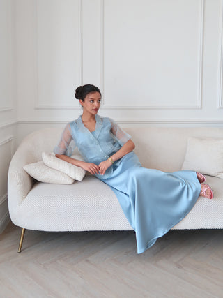 Light blue organza layered dress with satin skirt and sheer short sleeves, styled seated on sofa in minimal interior